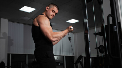 Portrait of an athlete, a sports man coach does an exercise on simulator in the gym. Healthy active lifestyle, shakes muscles. muscular shoulders