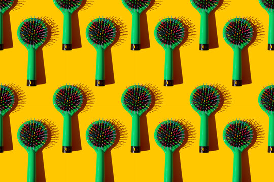 Studio shot of green hairbrushes against yellow background