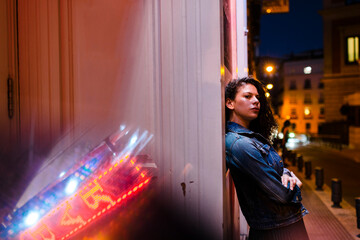 Young woman with arms crossed contemplating while standing by wall in city