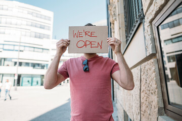 Shopkeeper holding cardboard with opening announcement in the city