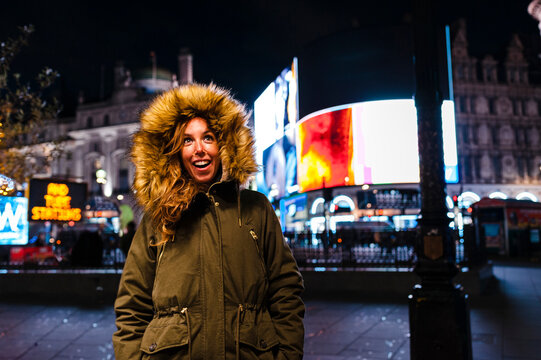 Smiling woman in warm clothing standing on Regent Street during Christmas at London, UK