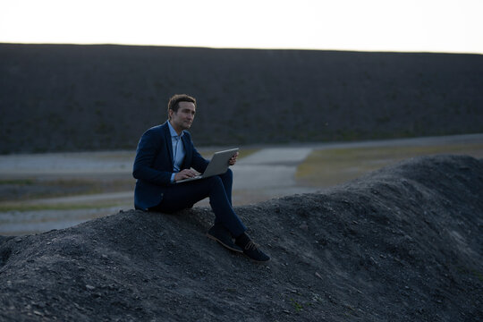 Mature businessman using laptop on a disused mine tip
