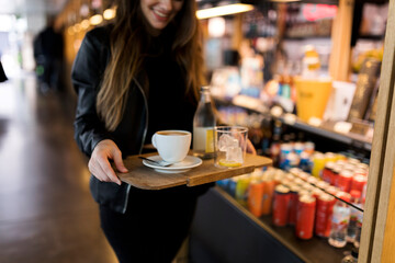 Close-up of woman carrying tray with coffee and soft drink in a self service cafe