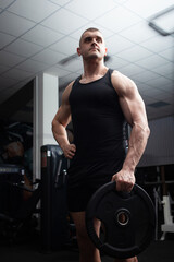 Fototapeta na wymiar Portrait of a handsome man in gym. Coach, athlete, bodybuilder, muscular sexy body, darkness. serious