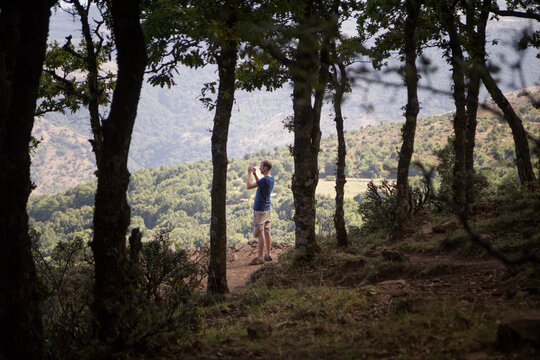 Italy, Sicily, Castelbuono, Parco delle Madonie, young man taking a photo with smartphone