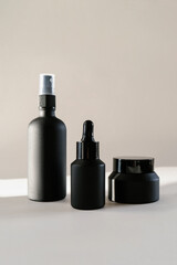 Black cosmetic bottles on a background flooded with sunlight.