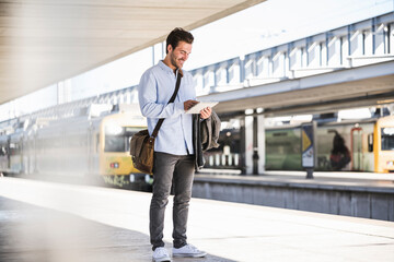 Casual young businessman using tablet at the train station
