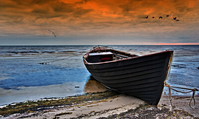 Old fishing boat on the beach at sunset