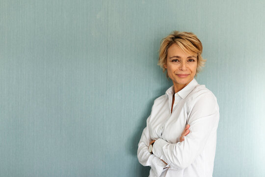 Portrait of confident mature woman standing at a wall