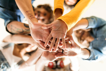 Group of happy friends huddling and stacking hands