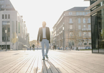 Businessman walking in the city at sunset
