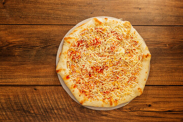 Simple cheese pizza on a cardboard base on a wooden table surface. Frozen product. Italian style fast food.