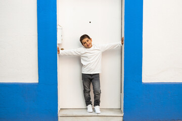 Little kid in front of a blue and white door