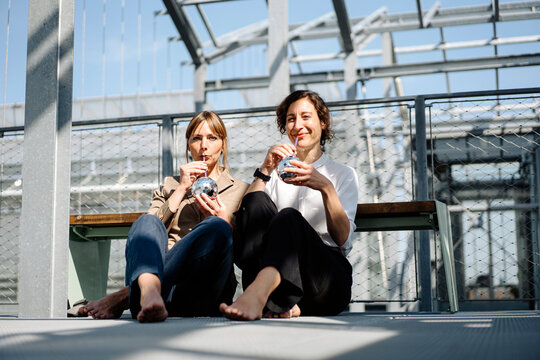 Two businesswomen having a drink at a metal construction outdoors