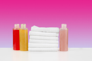 Pile of towels, bottles with shampoo on white table