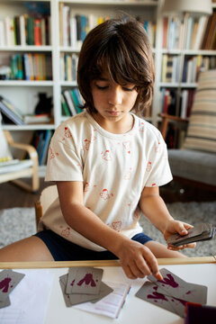 Portrait of boy sitting at table with playing cards at home