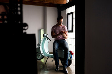 Man with motor scooter reading a book in a loft