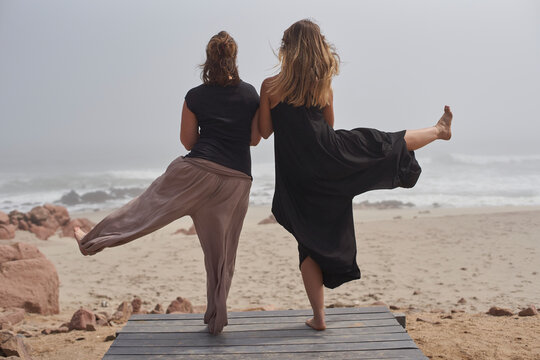 Rear view of two women doing yoga at the ocean, Cape Cross, Namibia