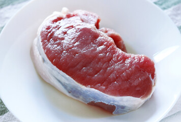 Slice fresh frozen pork on a plate in the kitchen table.