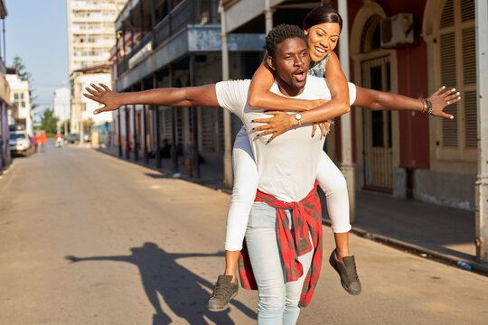 Young man carrying girlfriend piggyback in the street, Mabuto, Mozambique