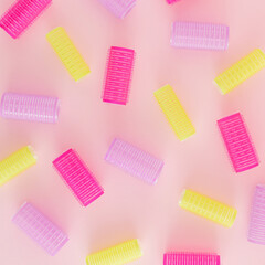 Creative pattern made of colorful hair curlers on a pastel pink background. Minimal retro fashion concept. Salons and hairstyle inspiration.