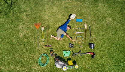 View from above of a gardener in laying on the grass with all the tools he need for take care of garden