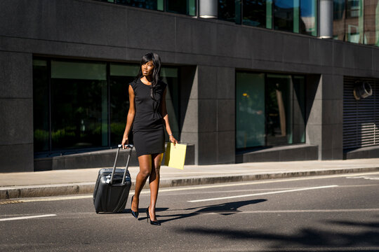 Businesswoman with trolley crossing road