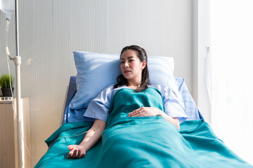 Woman patient lying give salt water on the hospital bed and her hand with medical drip intravenous...