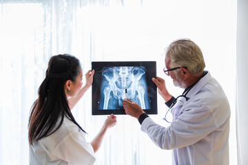 Senior male doctor and Asian nurse doing analysis x-ray scan photo patient in the office at hospital. Health care concept