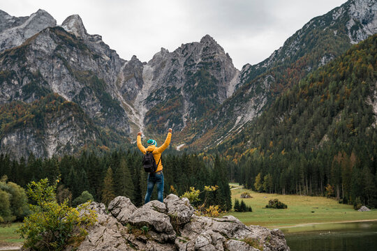 Hiker on viewpoint with raised arms at Laghi di Fusine, Friuli Venezia Giulia, Italy