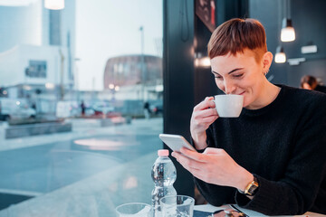 Redheaded young woman using smartphone in a cafe
