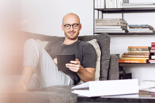 Man sitting at home on a couch using digital tablet