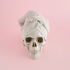 A creative arrangement  made of skull and towel on a pink background. Minimal Halloween concept. Salon and beauty Inspiration.