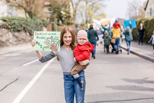 Girl with baby on her arm holding a placard on a demonstration for environmentalism
