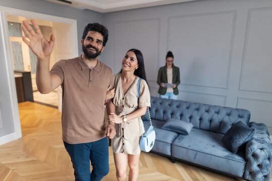 Young Happy Couple Looking Around The Apartment During Real Estate Showing.