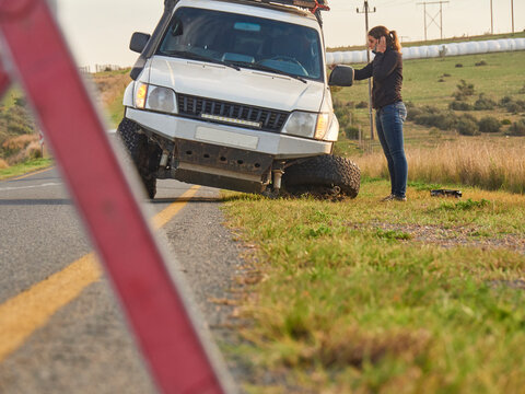 Safety triangle warning of a car accident on the side of the road with woman on the phone, South Africa
