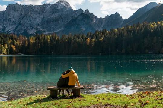 Rear view of couple sitting on bench at Laghi di Fusine, Friuli Venezia Giulia, Italy