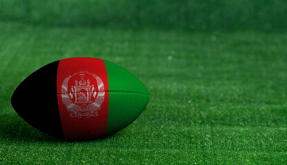 American football ball  with Afghanistan flag on green grass background, close up