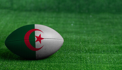 American football ball  with Algeria flag on green grass background, close up