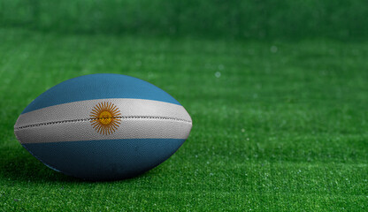 American football ball  with Argentina flag on green grass background, close up