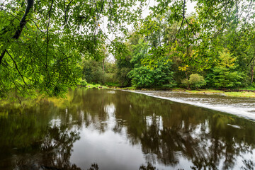 Fototapeta na wymiar River with trees around mirroring on waterground