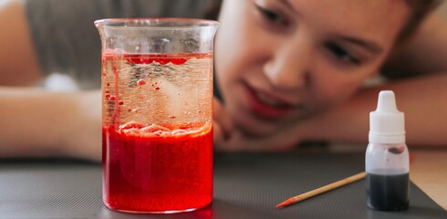 Lava lamp, science experiment with water, food coloring, oil and aspirin doing by school girl. Step by step process of doing homework. Education, back to school, distant banner.