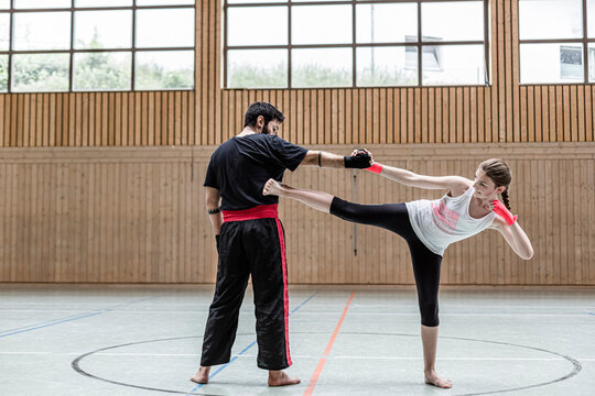 Female Kickboxer Sparring With Coach In Sports Hall