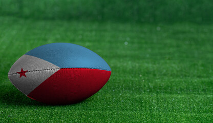 American football ball  with Djibouti flag on green grass background, close up
