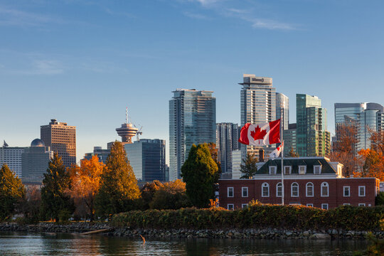 Downtown Vancouver modern Coal Harbor business district area high office and apartment buildings with Naval Museum with a large Canadian flag and fall foliage autumn