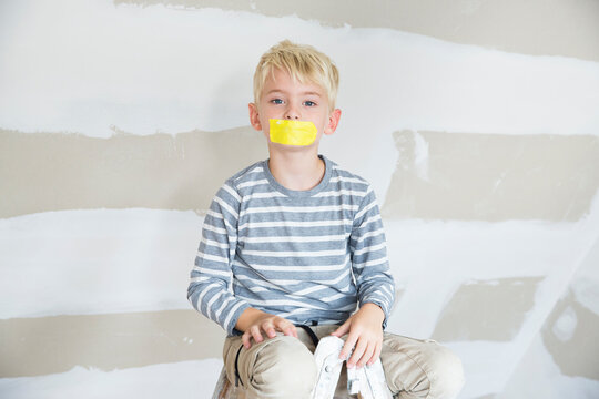 Portrait of boy with taped mouth sitting on ladder in attic to be renovated