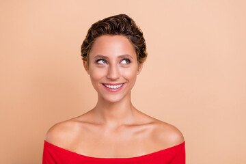 Photo of happy pretty charming young woman look empty space inspired isolated on pastel beige color...