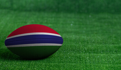 Fototapeta na wymiar American football ball with Gambia flag on green grass background, close up