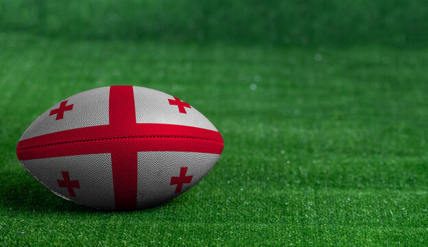 American football ball  with Georgia flag on green grass background, close up