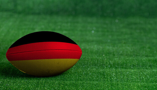 American football ball  with Germany flag on green grass background, close up